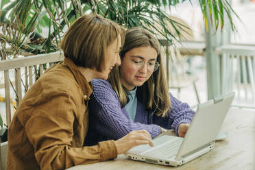 Mutter und Tochter benutzen Laptop in einem Cafe - VSNF00739