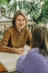 Mutter und Tochter sitzen und diskutieren im Café - VSNF00740
