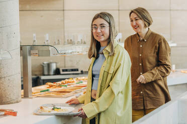 Smiling mother and daugther taking food at buffet in cafe - VSNF00742