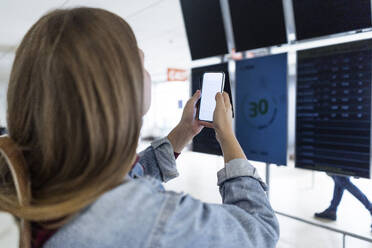 Junge Frau fotografiert Ankunfts-Abflugtafel am Flughafen - JJF00864