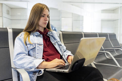 Junge Frau benutzt Laptop in der Flughafenlobby - JJF00871