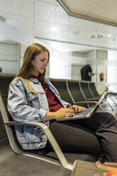 Frau mit Laptop auf dem Sitz im Flughafen sitzend - JJF00872