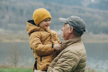 Großvater trägt Enkel in warmer Kleidung - VSNF00751