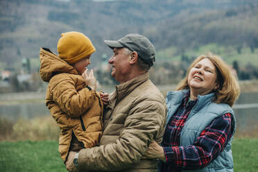 Großeltern haben Spaß mit ihrem Enkel, der warme Kleidung trägt - VSNF00752