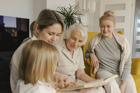 Mehrgenerationenfamilie mit Fotoalbum zu Hause - VIVF00573