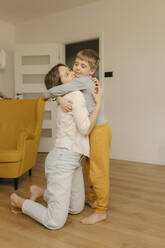 Boy embracing mother kneeling at home - VIVF00597