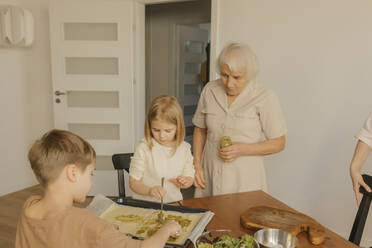 Mehrgenerationenfamilie bei der Essenszubereitung zu Hause - VIVF00635