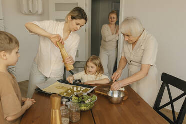 Frau bestreut das Essen ihrer Familie zu Hause mit Pfeffer - VIVF00639