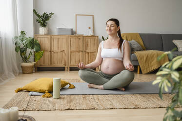 Pregnant woman practicing Lotus position at home - ALKF00194