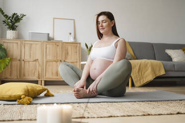 Schwangere Frau bei der Meditation mit geschlossenen Augen zu Hause - ALKF00210