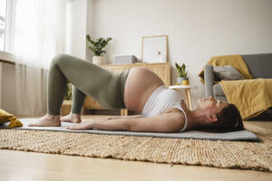 Pregnant woman doing prenatal yoga on exercise mat at home - ALKF00211