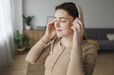 Schwangere Frau mit Sommersprossen passt Kopfhörer zu Hause an - ALKF00217