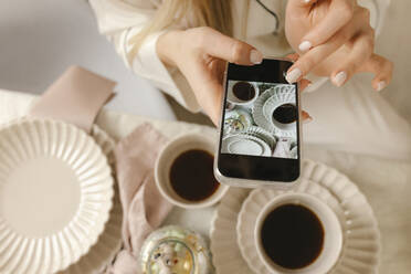 Woman taking picture of coffee through smart phone at home - VIVF00654