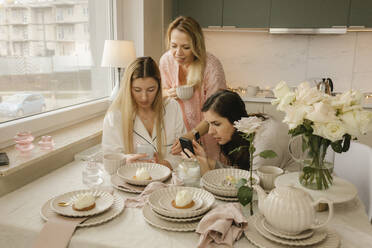 Freunde fotografieren Kuchen mit dem Smartphone in der Küche zu Hause - VIVF00663
