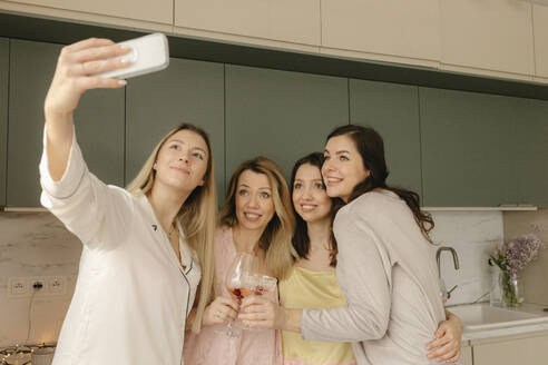 Frau nimmt Selfie durch Smartphone mit Freunden in der Küche zu Hause - VIVF00671