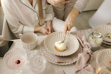 Woman having cake on plate by friend at dining table at home - VIVF00675