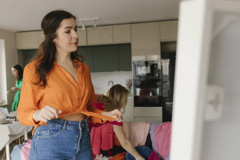 Frau probiert orangefarbenes Hemd zu Hause aus - VIVF00717