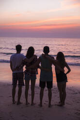 Freunde mit Arme um Blick auf Sonnenuntergang Blick auf den Strand - IKF00287