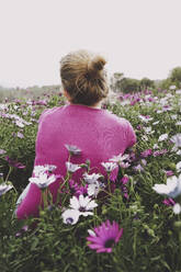 Woman with hairbun amidst colorful daisies in field - SVCF00379