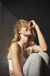 Blonde junge Frau lachend im Sonnenlicht - PNEF02734