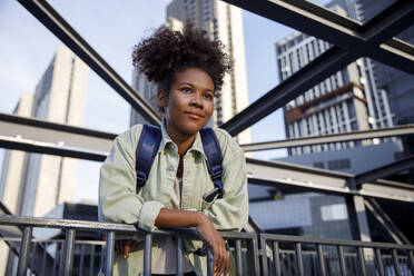 Woman with curly hair leaning on railing - IKF00297