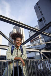 Smiling woman leaning on railing - IKF00298