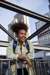 Contemplative young woman leaning on railing - IKF00299