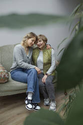 Grandmother and granddaughter sitting together in living room - OGF01284