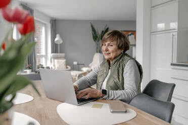 Senior woman doing online shopping through laptop at home - OGF01291