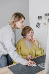 Enkelin am Computer mit Großmutter am Schreibtisch - OGF01300