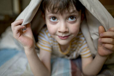 Cute boy lying under blanket at home - ANAF01274