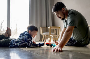 Vater und Sohn spielen mit Spielzeug zu Hause - ANAF01280