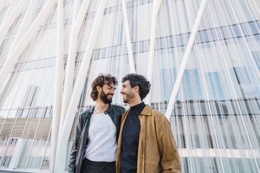 Schwule Männer sehen sich vor einem Gebäude stehend an - MMPF00717