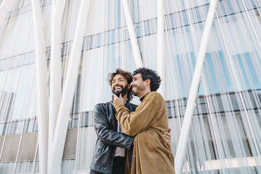 Glückliches, zärtliches schwules Paar vor einem Gebäude - MMPF00719