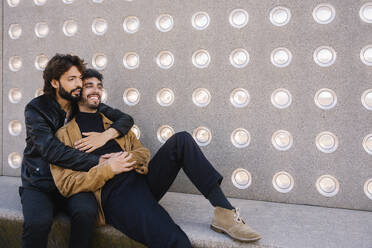 Homosexuelles Paar sitzt in der Nähe einer Betonwand - MMPF00736