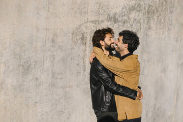 Romantische Homosexuell Paar stehen in der Nähe von Betonwand am sonnigen Tag - MMPF00739