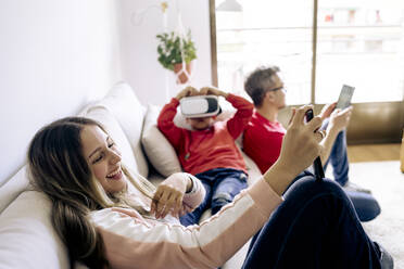 Happy girl using tablet PC sitting on sofa at home - JJF00898