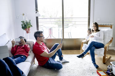 Family using wireless technologies in living room at home - JJF00899