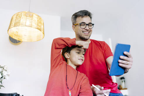 Vater und Sohn führen einen Videoanruf über einen Tablet-PC zu Hause - JJF00908