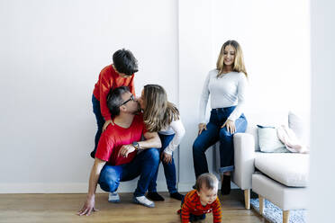 Father and mother kissing by children playing at home - JJF00918