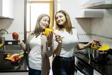 Mutter und Tochter bereiten zu Hause in der Küche stehend Essen zu - JJF00926