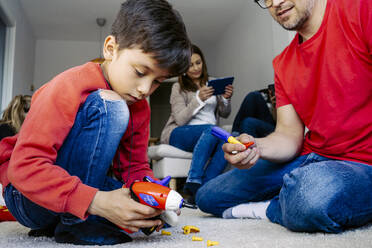 Father and son playing with toys sitting in living room at home - JJF00930