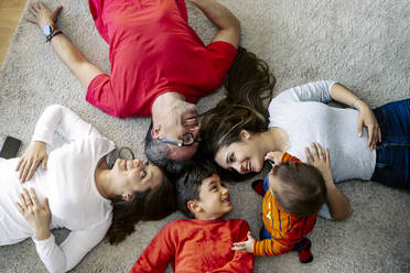 Glückliche Familie auf dem Teppich liegend zu Hause - JJF00934