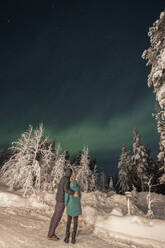 Couple looking at Aurora Borealis on sky at night - LHPF01517