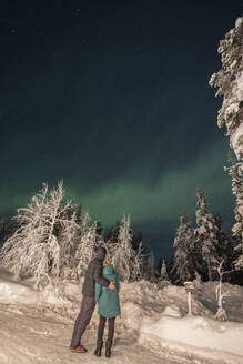 Ehepaar betrachtet Aurora Borealis am nächtlichen Himmel - LHPF01517