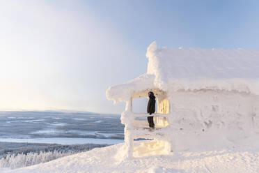 Mann steht auf Veranda schneebedeckten Haus auf Winter - LHPF01534