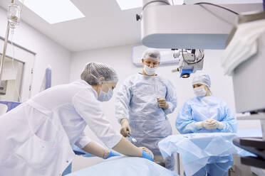 Doctor and nurse preparing for eye surgery in operating room - SANF00085