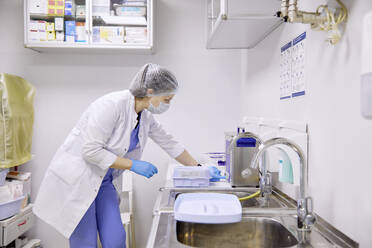 Chirurg arbeitet in der Nähe des Waschbeckens im Operationssaal - SANF00103