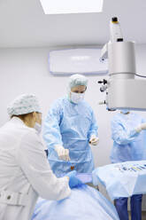 Colleagues assisting eye surgeon in operating room - SANF00104