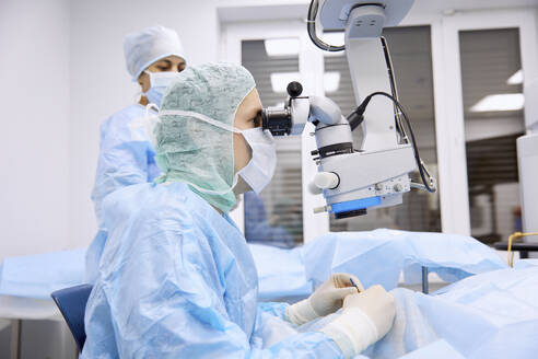 Surgeon performing eye surgery with microscope in operating room - SANF00105